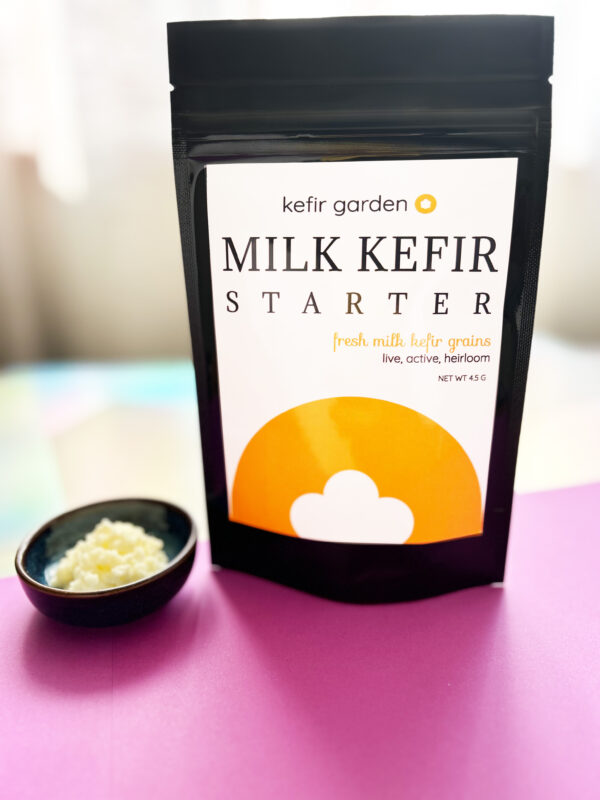 Photo of a stylized shot of our milk kefir grain packaging next to a small bowl of milk kefir grains